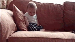 Video gif. A sleepy baby sitting on a couch falls face forward on the couch.