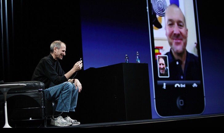 Bill Gates sitting on an in person presentation stage, FaceTiming a man that is being projected onto an LED screen