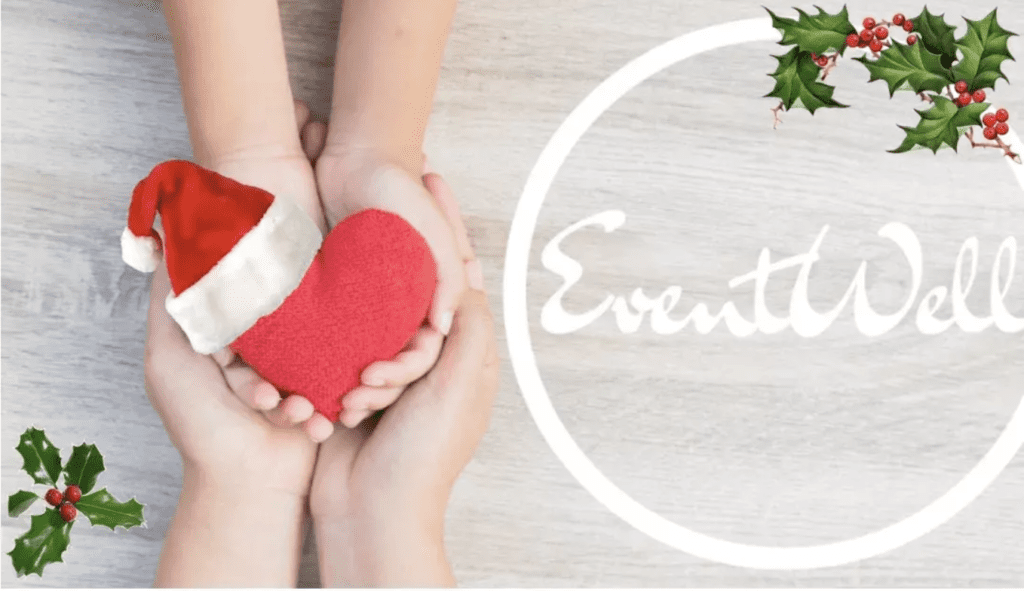 Picture of adult hands holding a child's hands that are holding a red heart with a Santa hat next to the "EventWell" logo