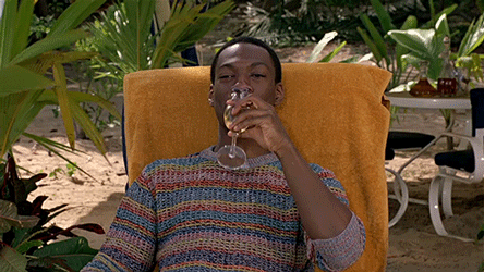 Eddie Murphy lounging on a chair outside, sipping a drink then wiping his lips