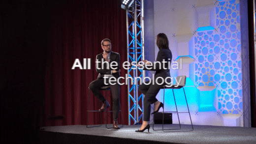GIF of man and woman talking on a speaker stage