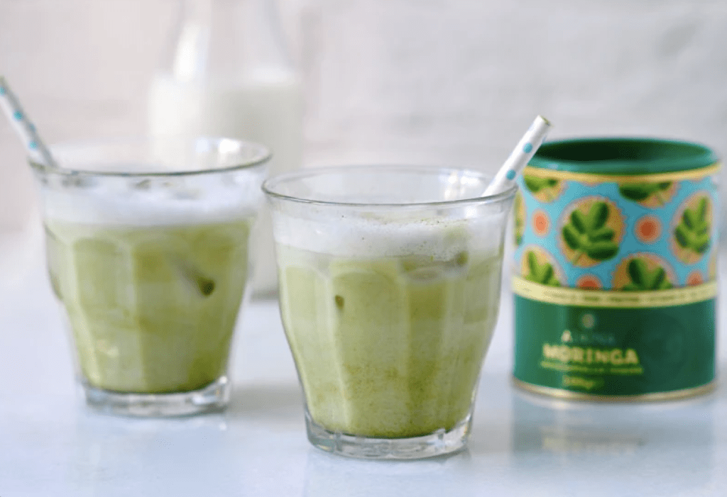 Two clear glasses with Matcha coffee, a Mooring can site behind them out of focus