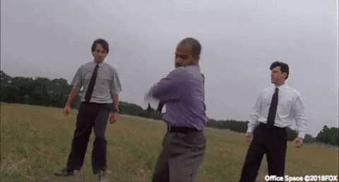 GIF of three men standing in a field with one smashing a computer with a baseball bat