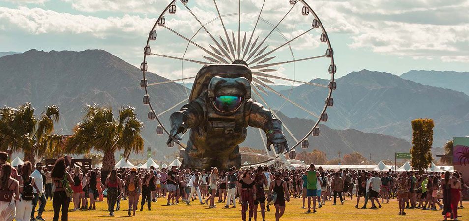 Image of Coachella with giant spaceman and ferris wheel in dessert. 