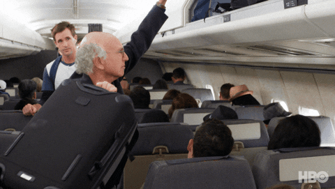 Man putting carry-on up on the plane.  